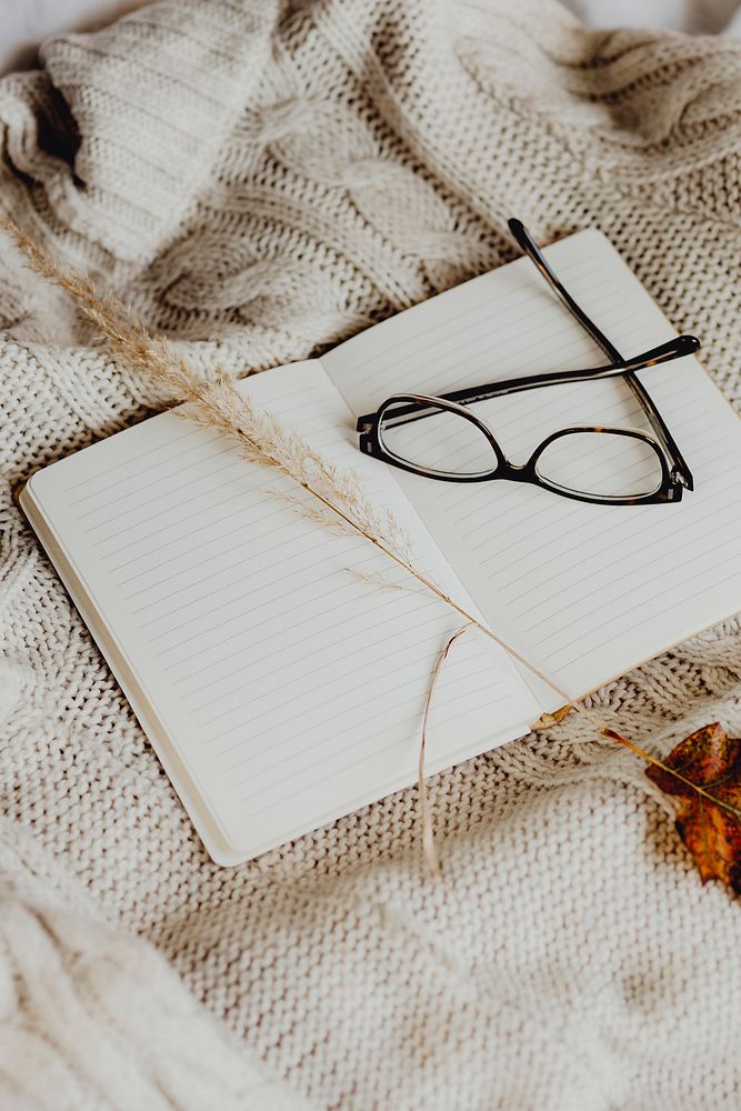 Eyeglasses and a notebook on a cream sweater