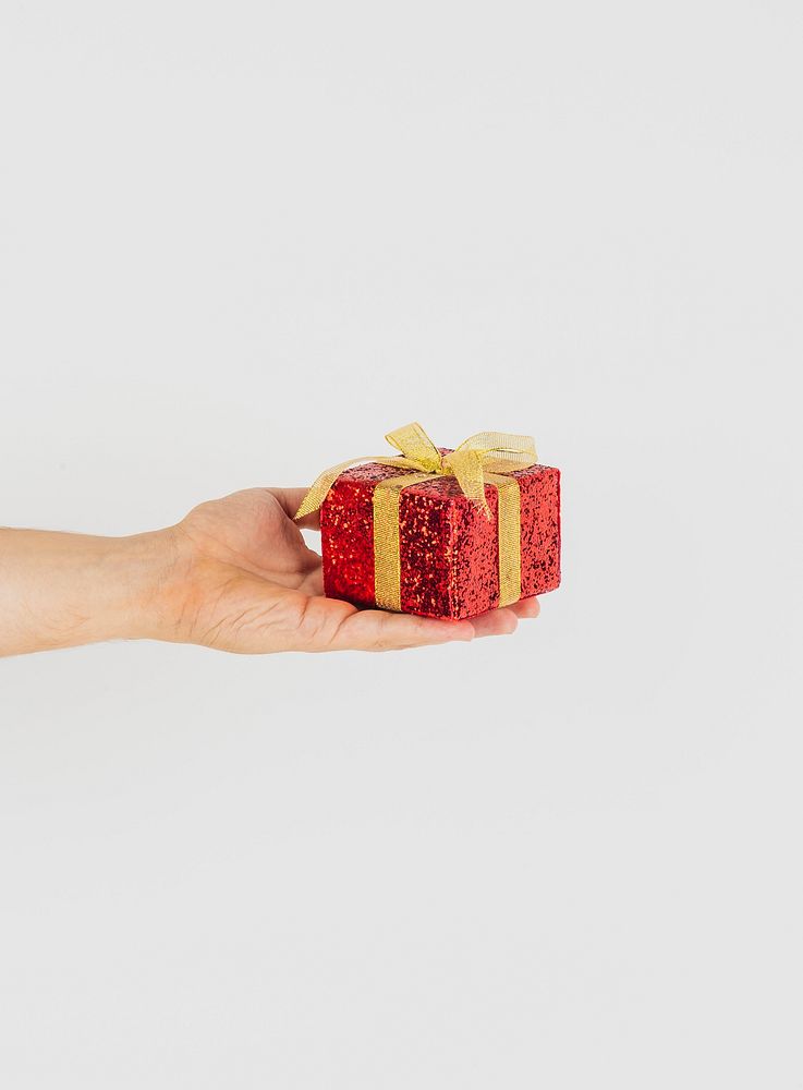 Hand holding red gift box with golden ribbon