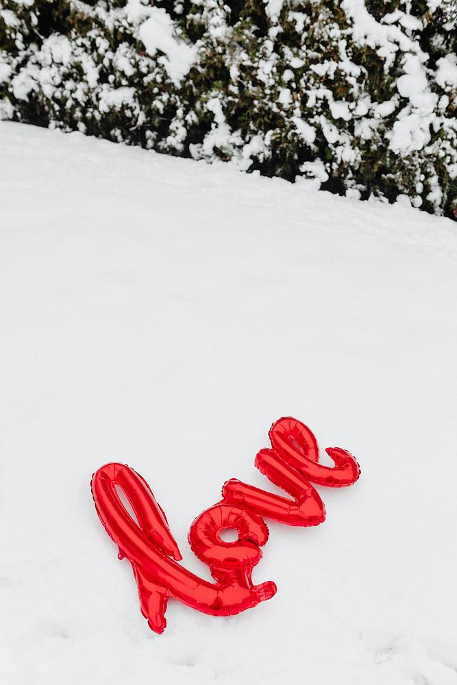Red love balloon word on a snowy ground