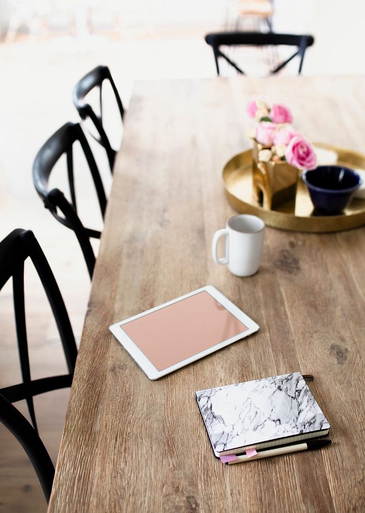 Digital tablet and a marble texture notebook on a wooden dining table