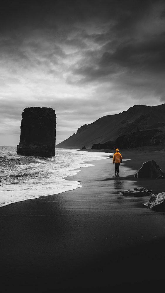 Man walking along a black beach in Iceland  mobile phone wallpaper