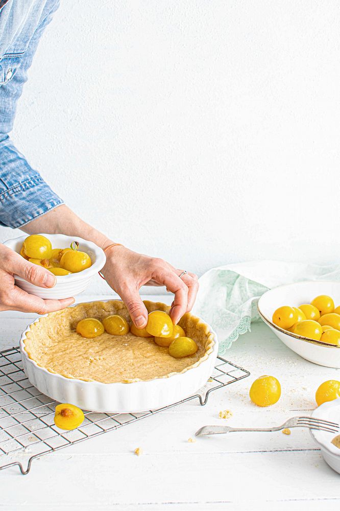 Woman filling pie crust with mirabelle plums
