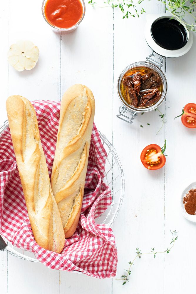 Fresh baguette in a basket by sun-dried tomatoes
