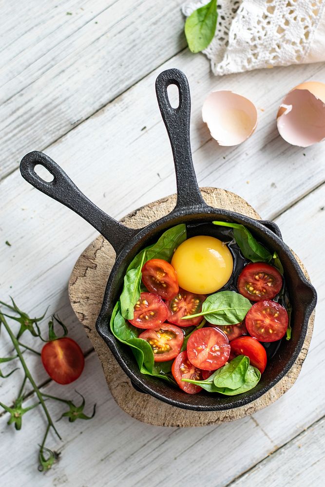 Raw egg and tomatoes in a pan