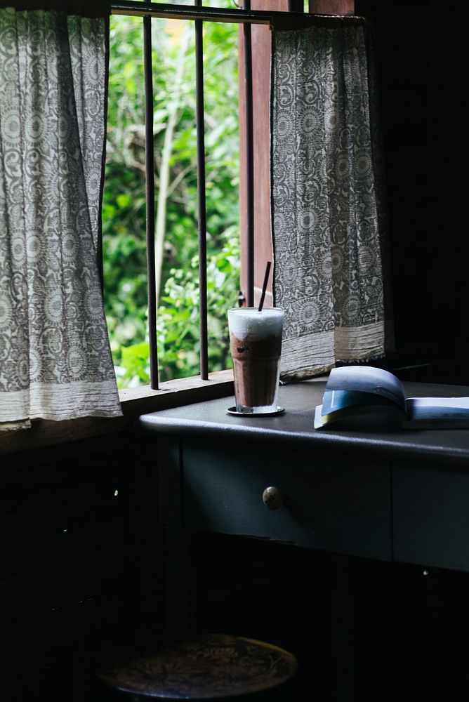 Iced chocolate on a table with a book by the window