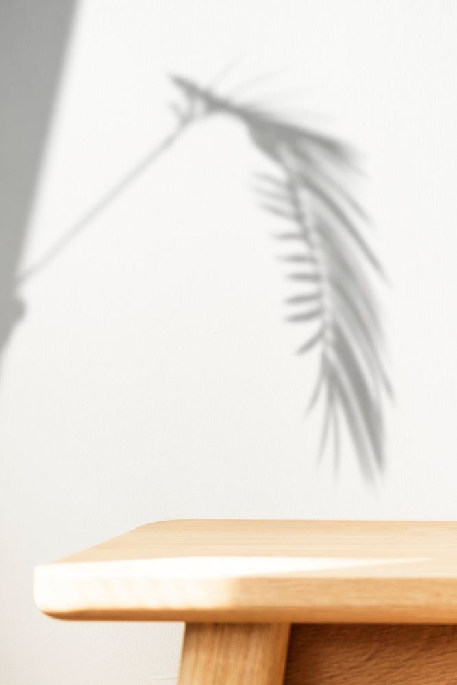 Wooden table with plant shadow on a wall