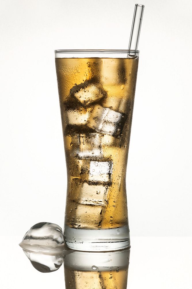 Cold carbonated drink over ice cubes in a glass with a straw 