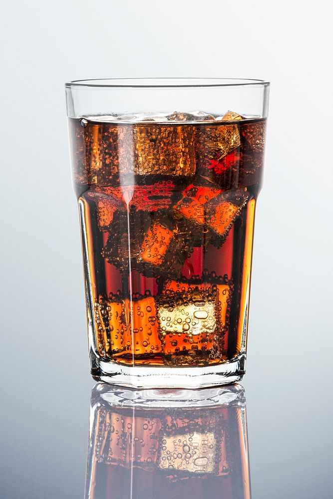 Cold carbonated drink over ice cubes in a  glass 