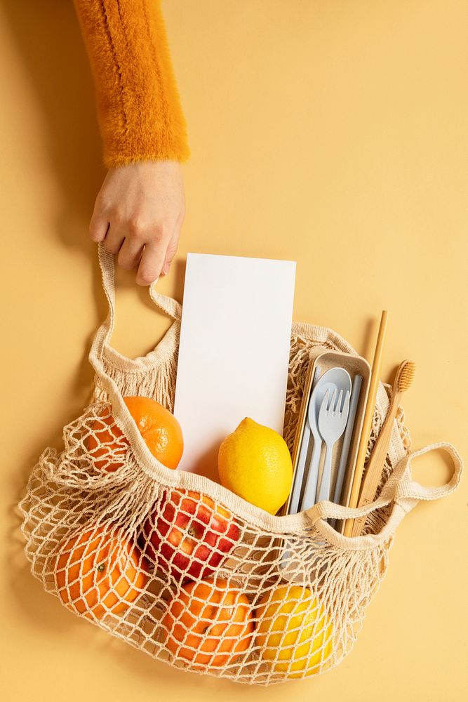 Reusable net bag full with fruits and eco-friendly travel utensils