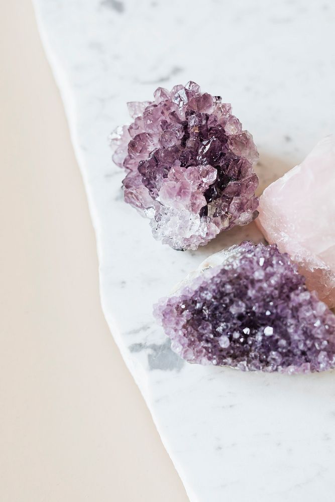 Rose quartz and amethyst healing crystals on a marble countertop