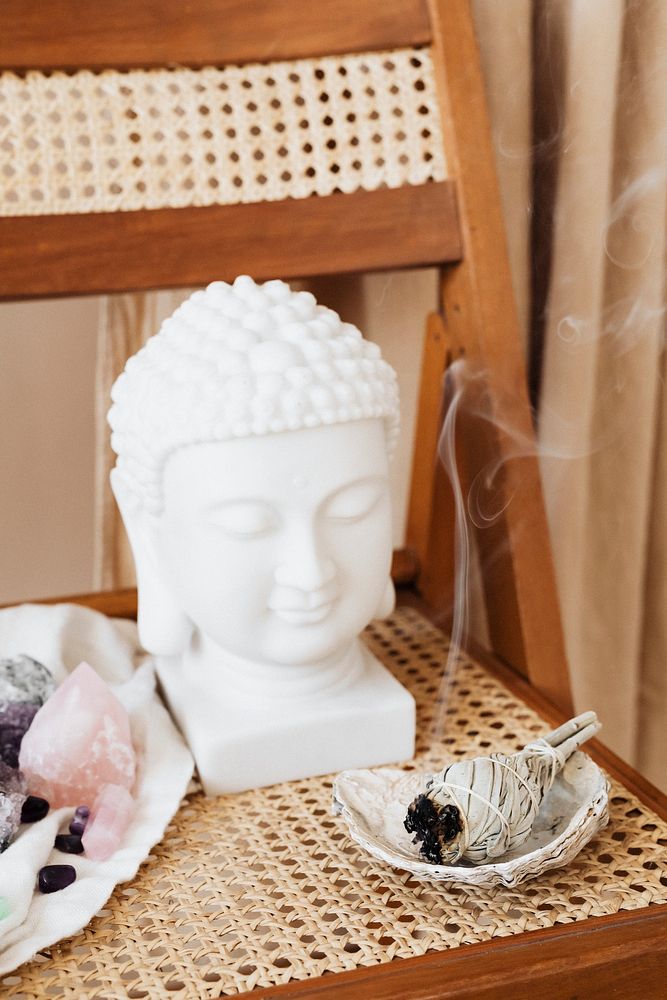 Buddha head statue by a burning sage smudge cleansing the house