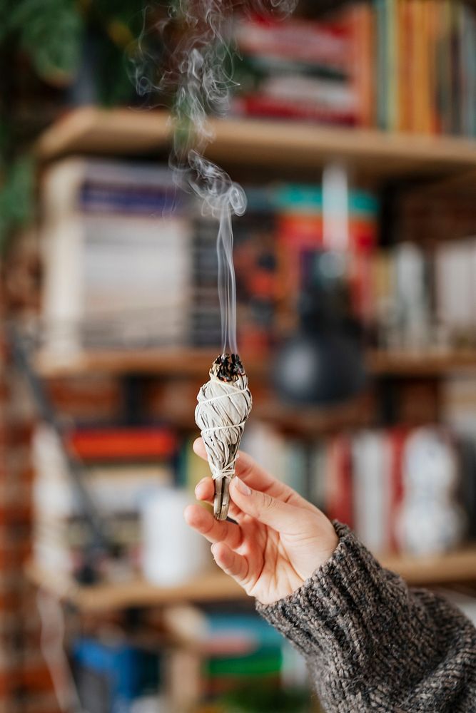 Woman burning sage smudge to cleanse the house