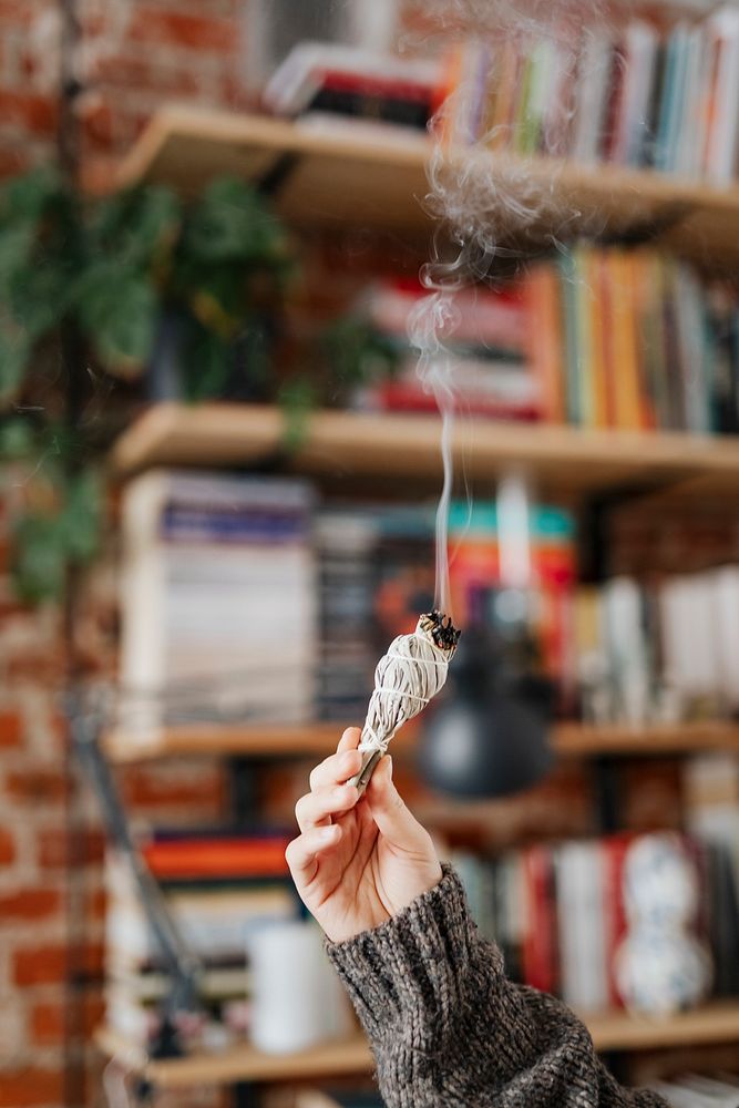 Woman burning sage smudge to cleanse the house