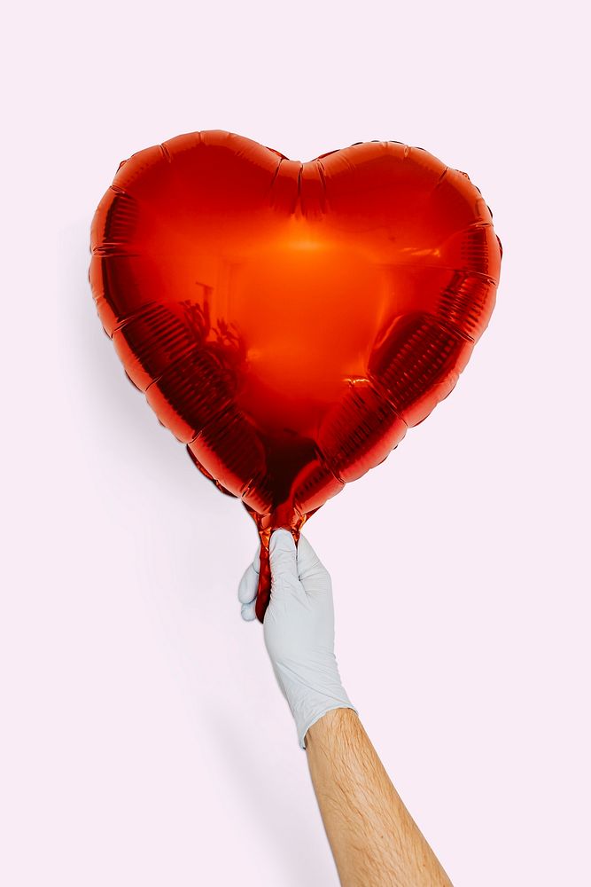 Gloved hand holding a red heart shaped balloon mockup