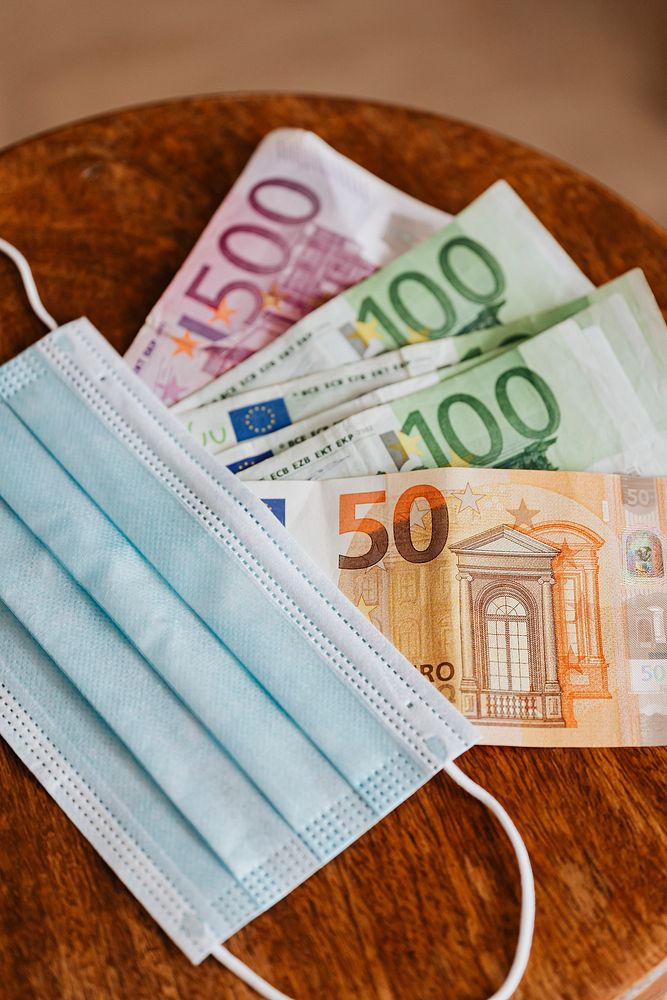 Euro banknotes with face masks on a wooden table