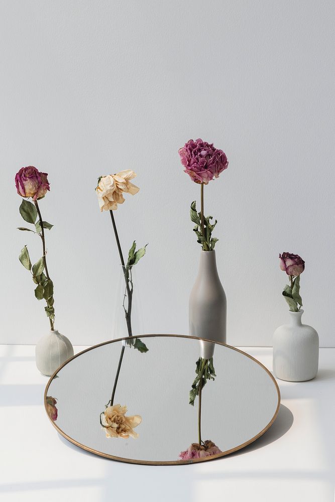 Dried flowers in minimal vases by a round mirror