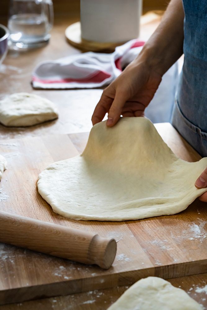 Baker holding a flat dough in kitchen closeup