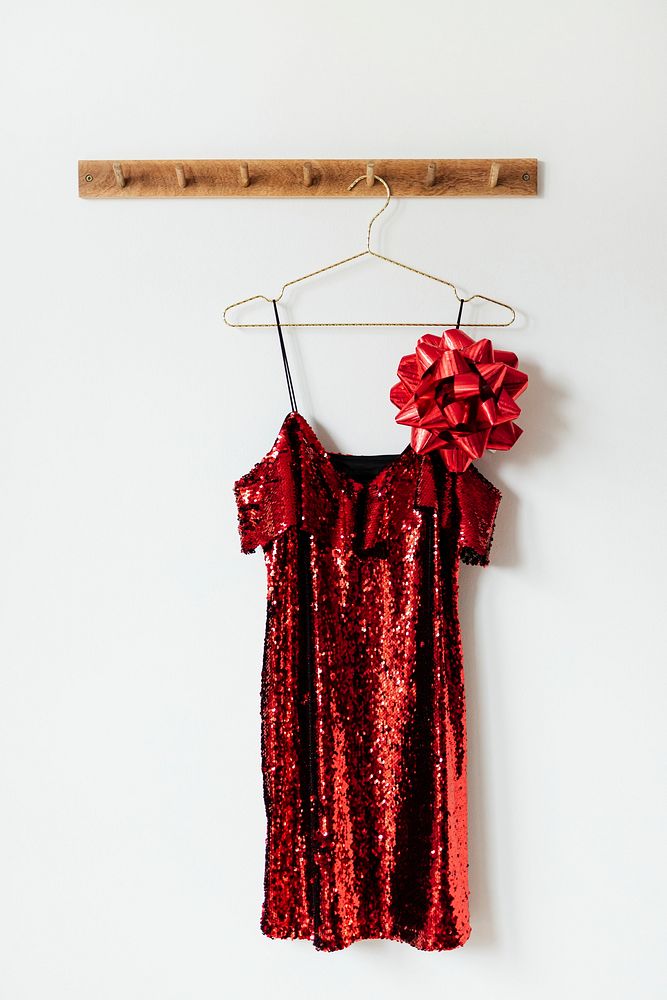 Red off shoulder sequin dress with a bow on a wall hanger