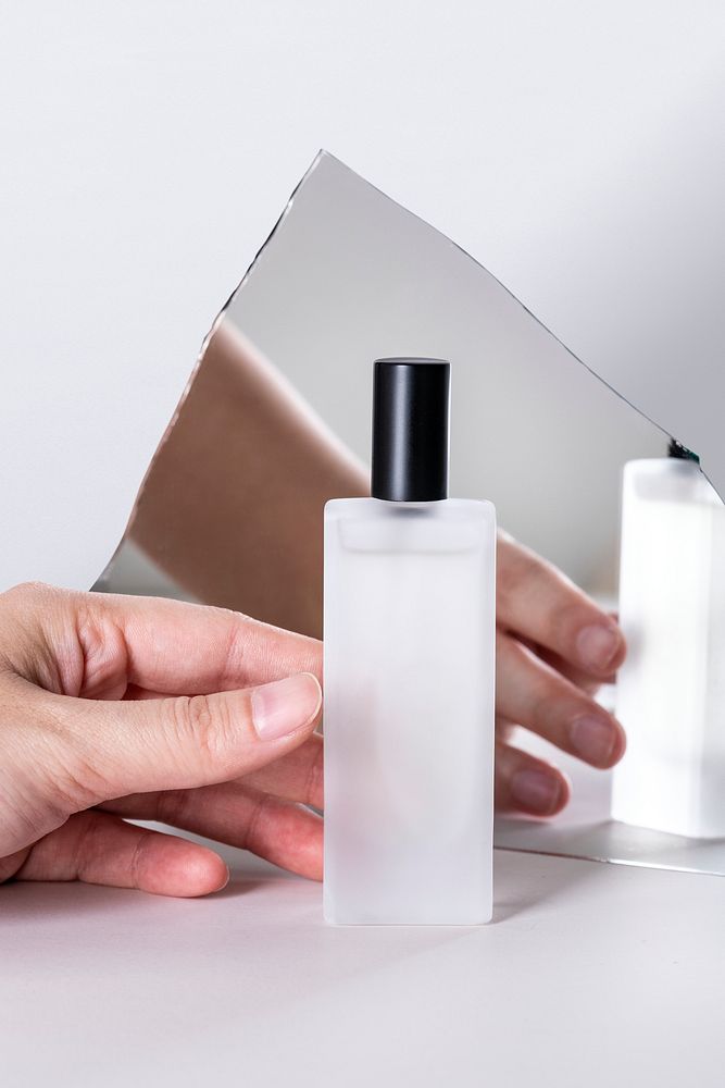 Cosmetic bottle held by hand in front of mirror shard
