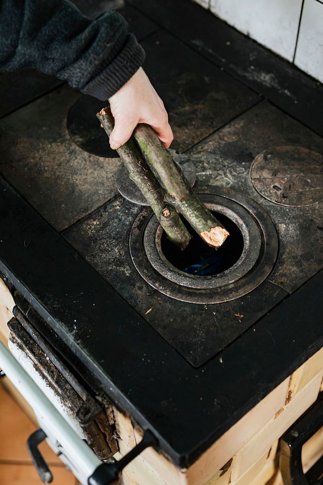 Woman putting sticks into the wood burning stove