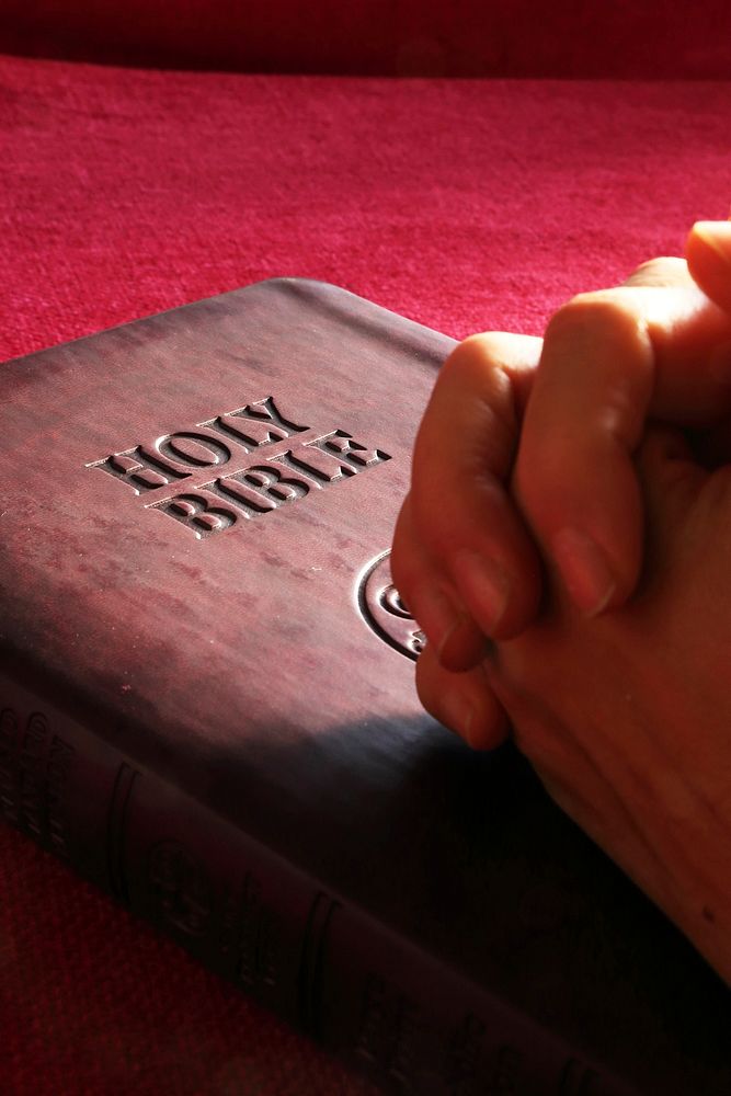 Free hands praying on bible photo, public domain CC0 image.