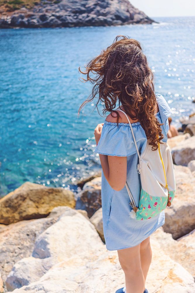 Free back of a girl standing on rock and watching the sea image, public domain CC0 photo.