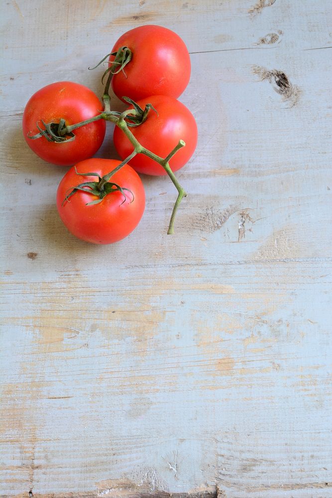 Free photo of red tomatoes with stem on a wooden table, public domain CC0 photo.