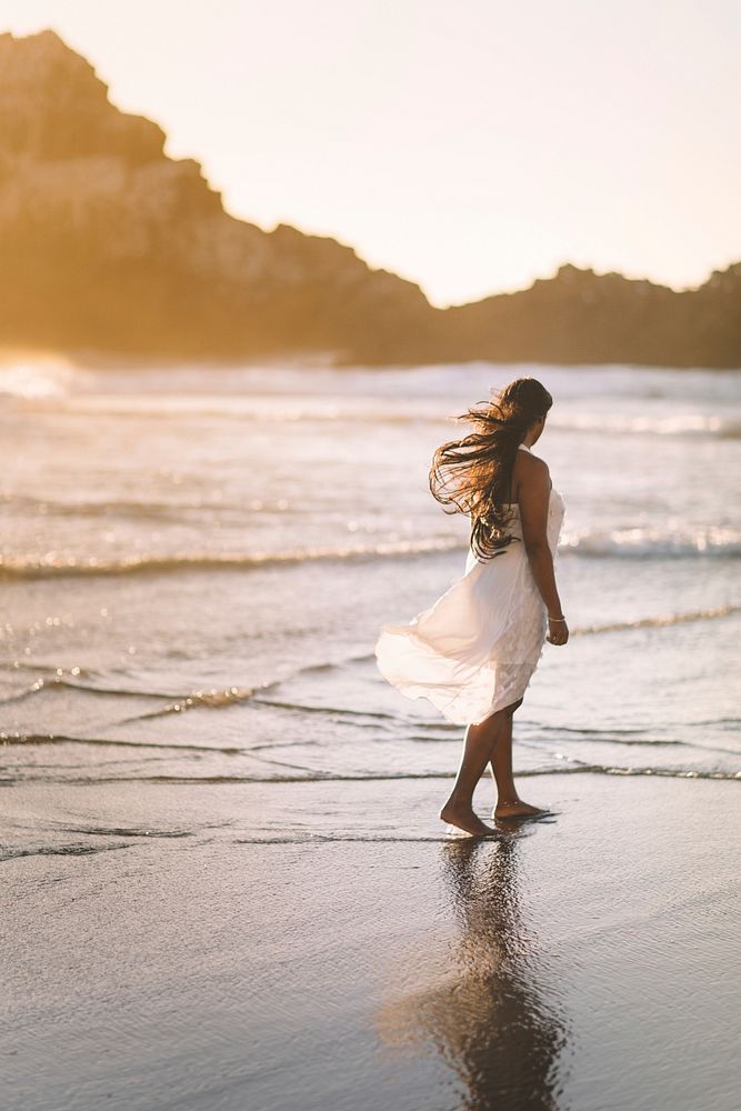 Woman in white dress walking at beach in sunset, free public domain CC0 photo.
