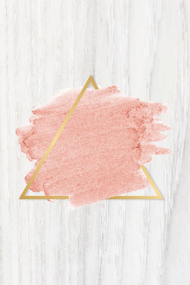 Pastel pink paint with a gold triangle frame on a bleached wood background
