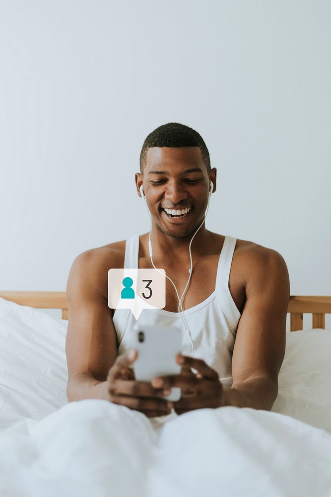 Happy man using social media on his smartphone while in bed