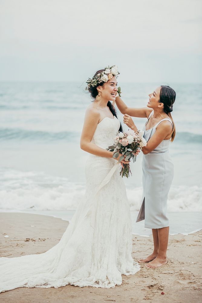 Cheerful bride and bridesmaid at the beach