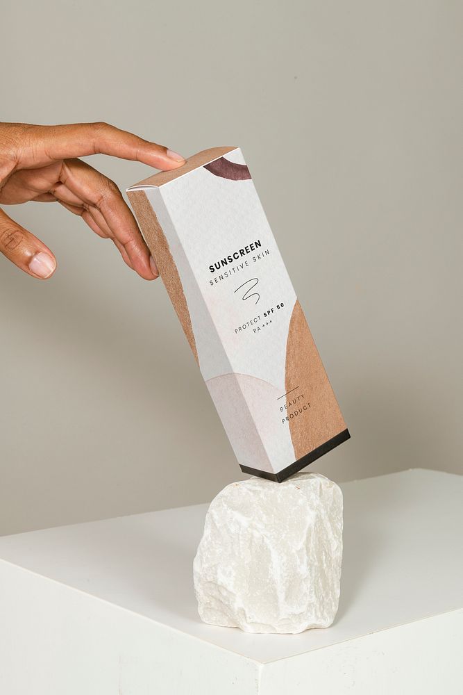 Watercolor patterned cosmetic packaging on a white rock