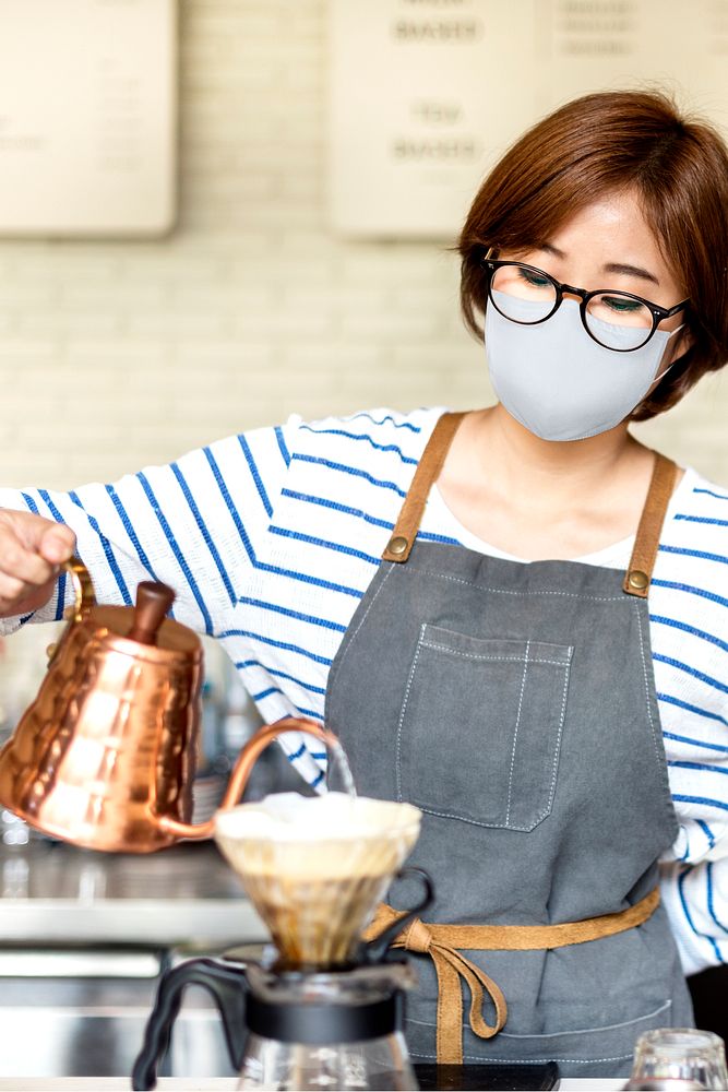 Korean barista in face mask pouring drip coffee at cafe in new normal