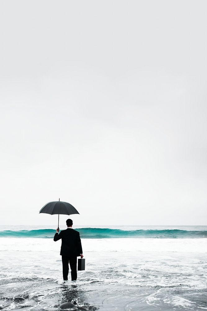 Formal businessman with umbrella standing in sea
