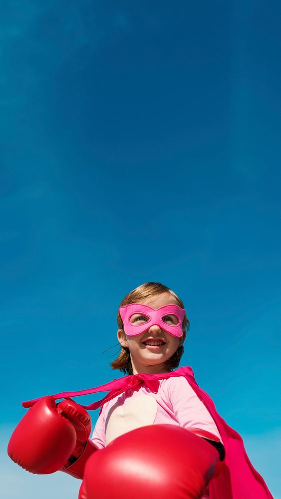 Superhero girl smiling on blue sky for education portrait