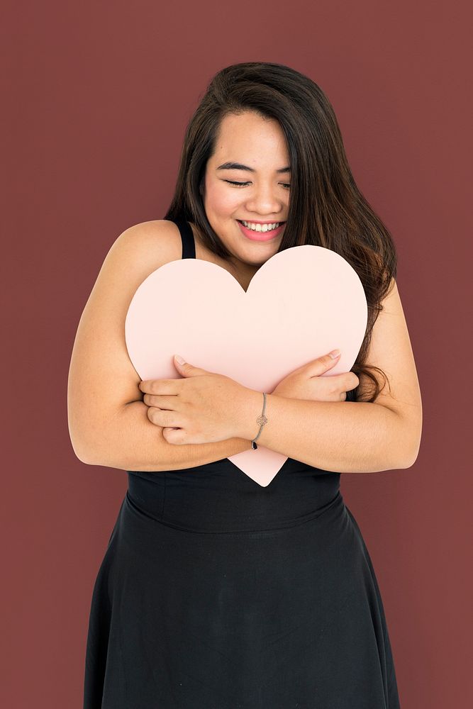 Portrait of a young woman hugging a heart shaped placard