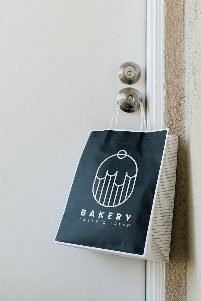 Contactless delivery bakery bag mockup hanging on a doorknob during the coronavirus pandemic