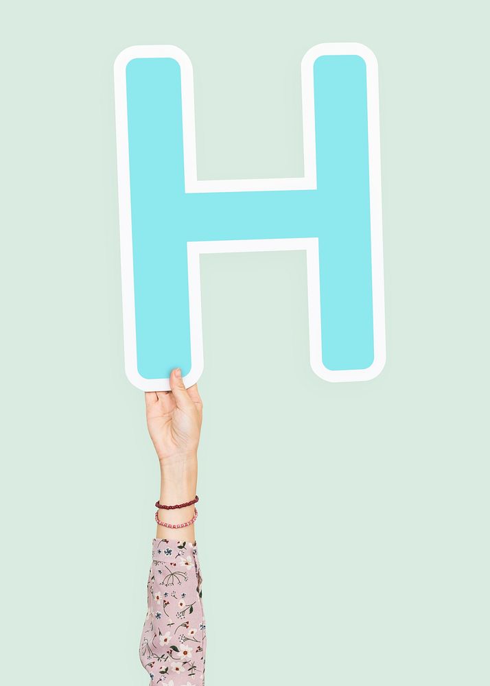 Hand holding H sign, isolated on light green