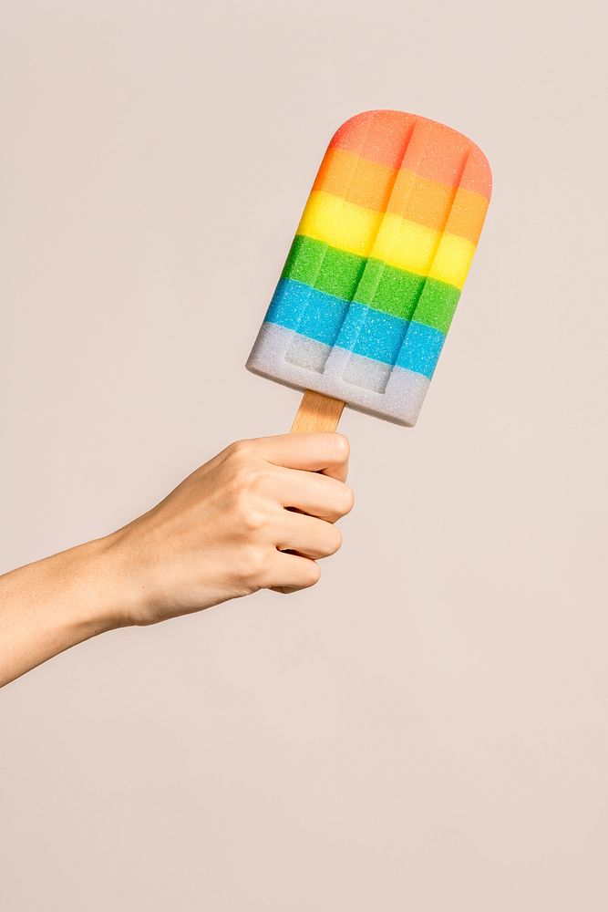 Hand with a rainbow ice pop in summertime