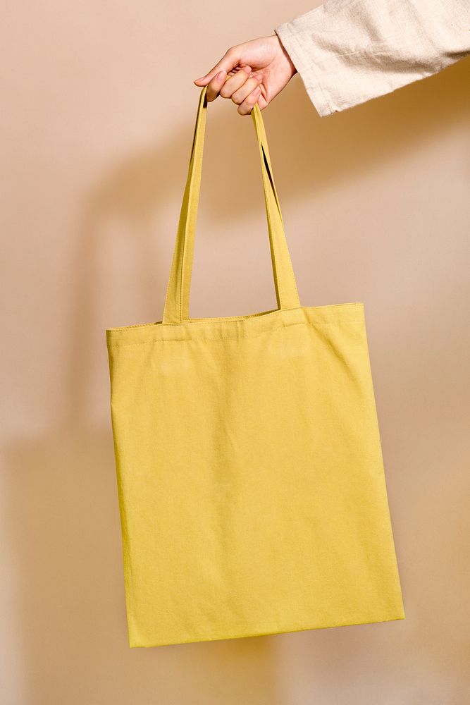 Woman holding a yellow tote bag in her hand