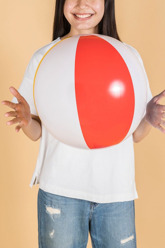 Woman in a white tee holding a beach ball on a beige background