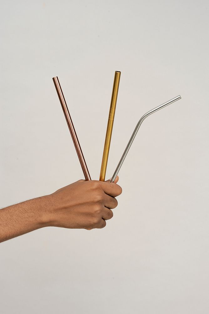 Hand holding reusable metal straws