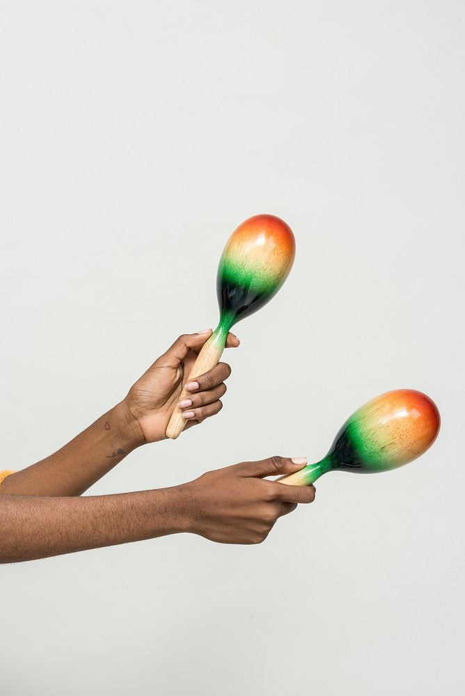 Black hands holding maracas isolated on a gray background