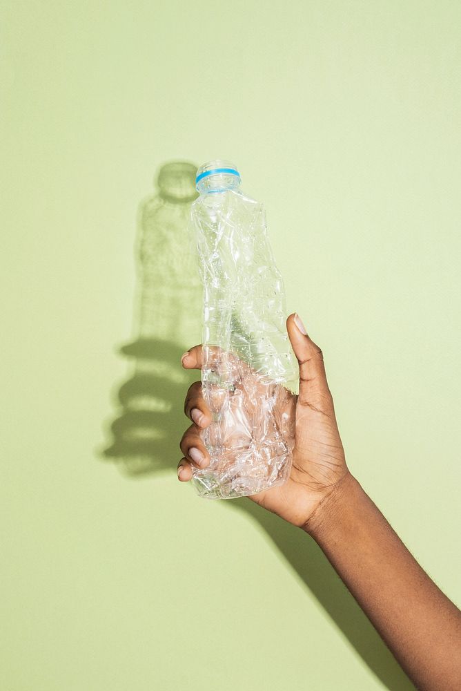 Hand holding a crushed plastic bottle