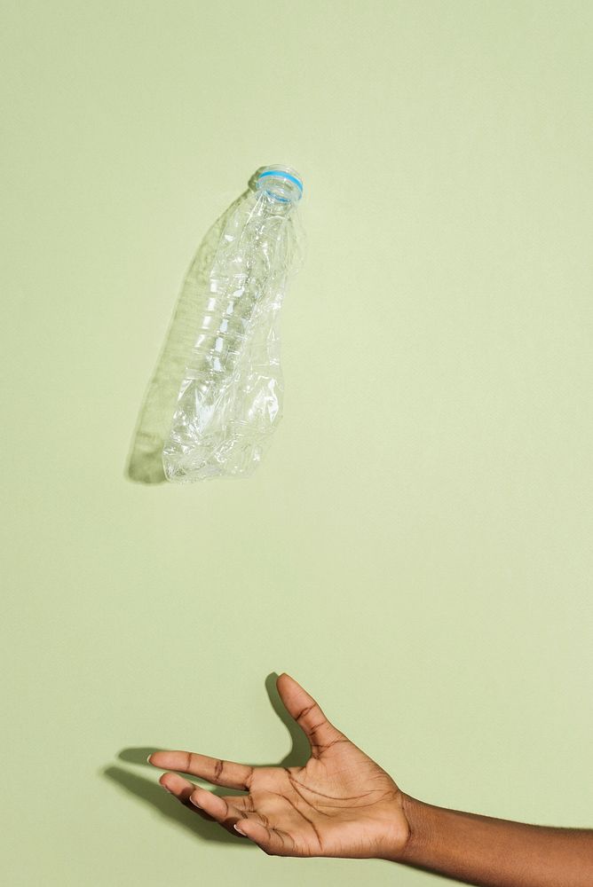 Hand catching a falling crushed plastic bottle