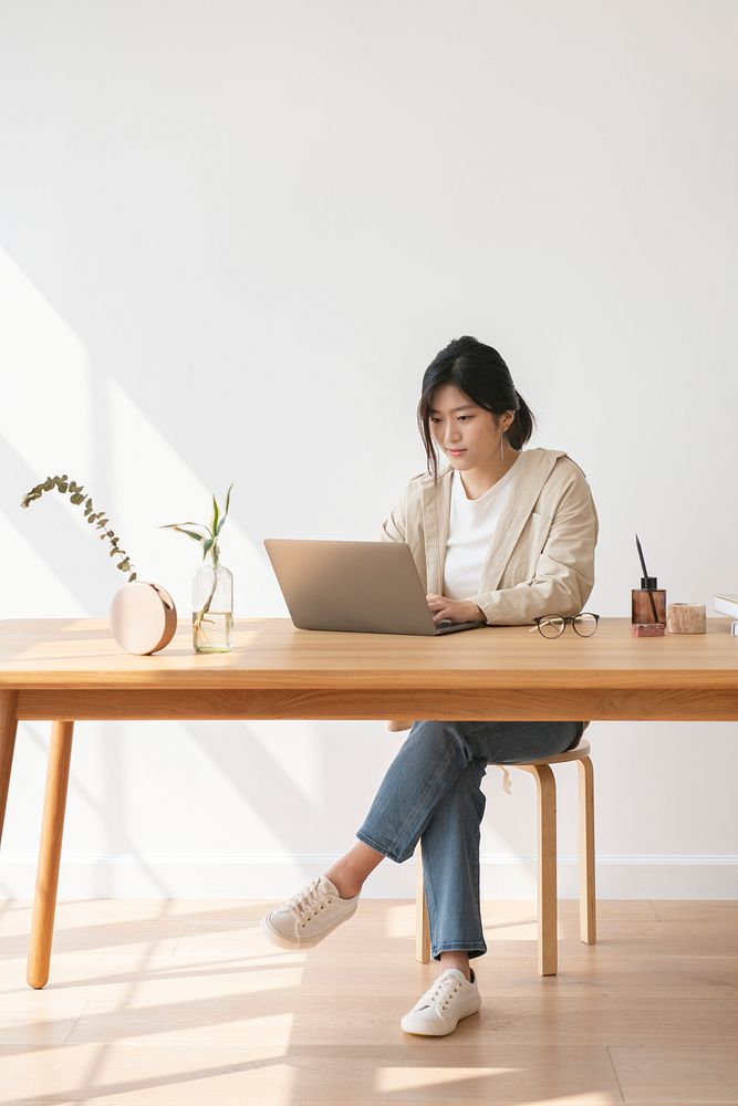 Happy Asian woman working at home using a laptop