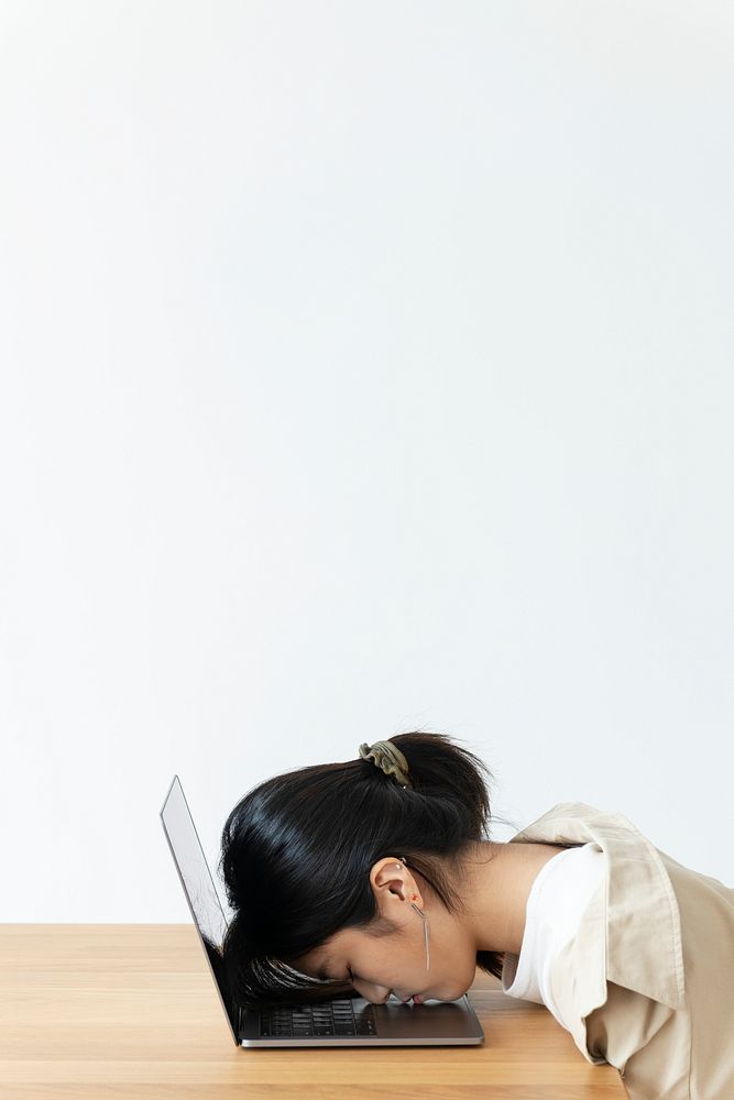 Stressed Asian girl resting her head on a laptop