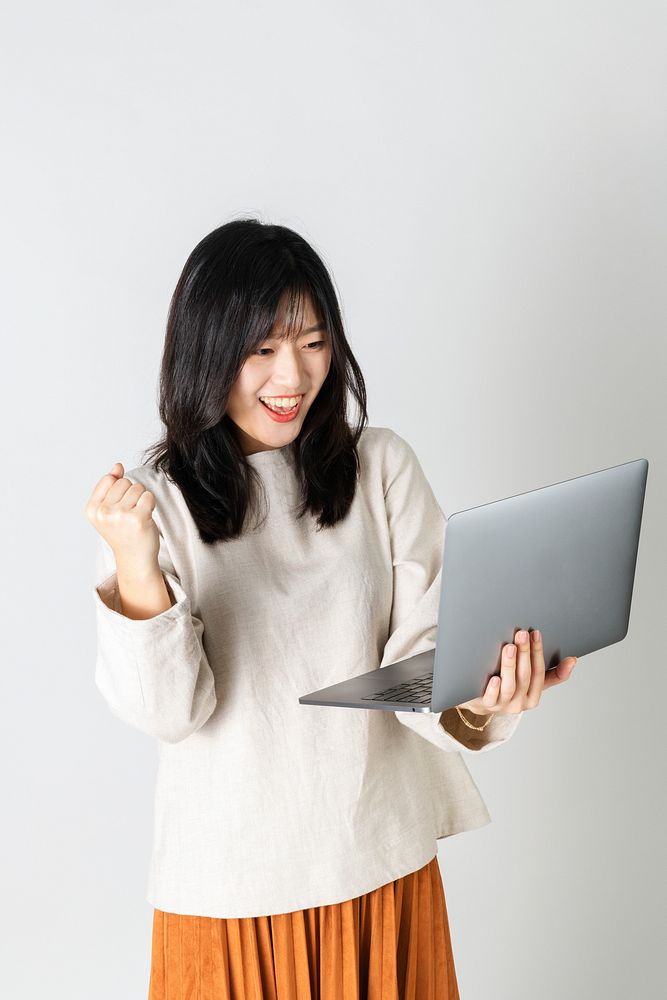 Excited Asian woman using a laptop 