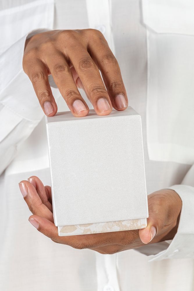Hands holding a white blank cosmetic packaging