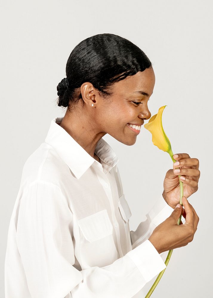 Happy black woman smelling a yellow calla lily flower
